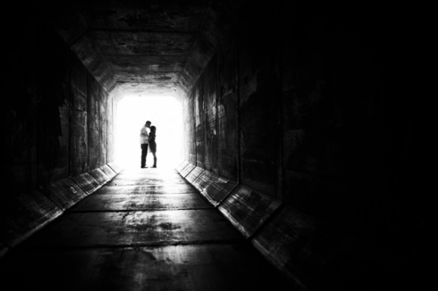 couple kissing in distance through tunnel