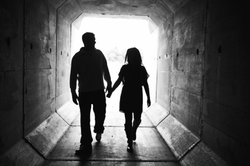 couple holding hands and walking through tunnel