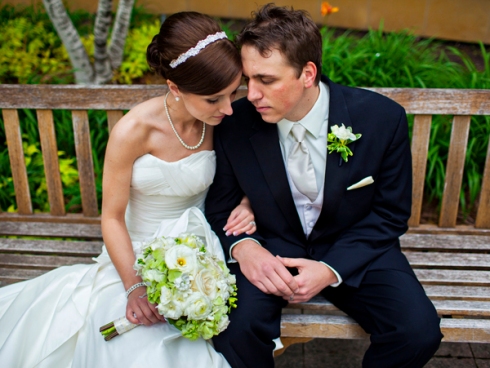 bride and groom sitting on wood bench